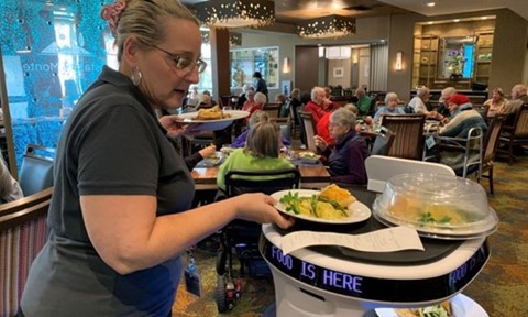 Woman serves food using Servi Plus robot